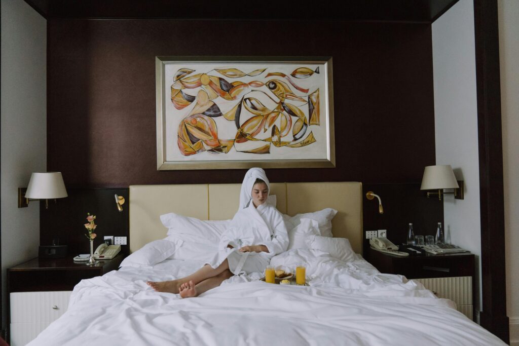 Woman enjoying breakfast in bed in a luxurious hotel setting, embracing relaxation and comfort.