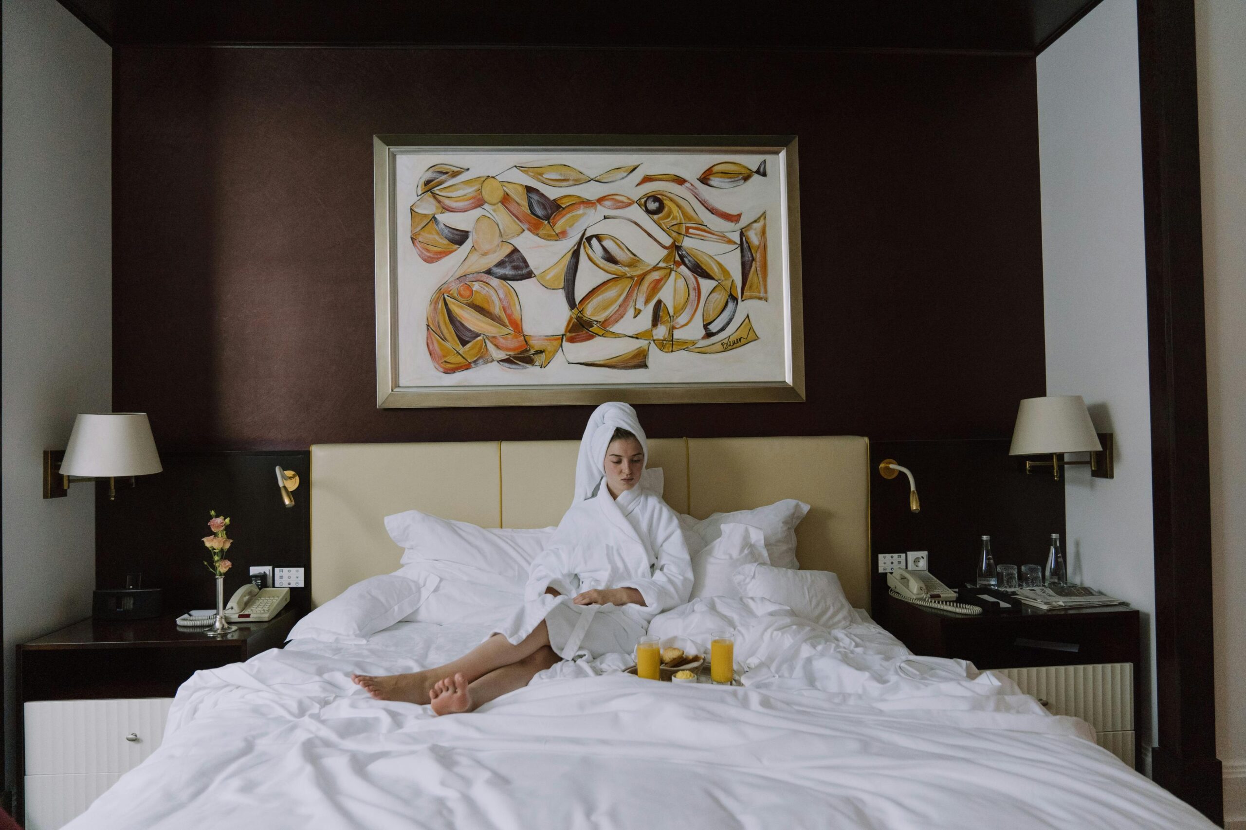 Woman enjoying breakfast in bed in a luxurious hotel setting, embracing relaxation and comfort.