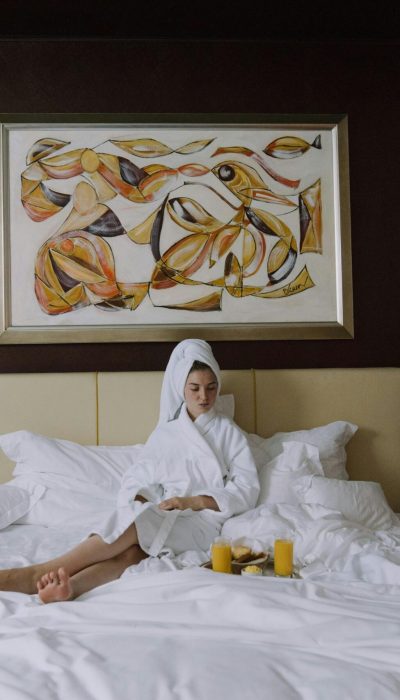 Woman enjoying breakfast in bed in a luxurious hotel setting, embracing relaxation and comfort.